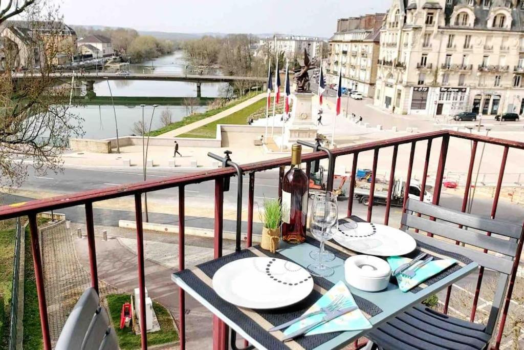 a table on a balcony with a view of a city at T1 cocooning à l’Hôtel de Ville in Charleville-Mézières