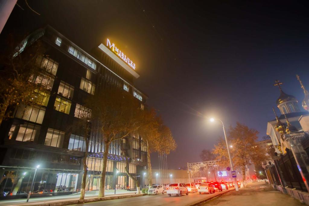 a city street at night with a building and cars at Mir Luxe Plaza in Tashkent