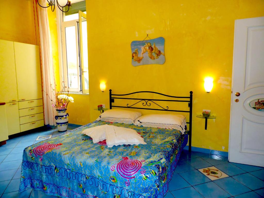 ein Schlafzimmer mit einem Bett in einem gelben Zimmer in der Unterkunft Dimora Carlo III in Vietri