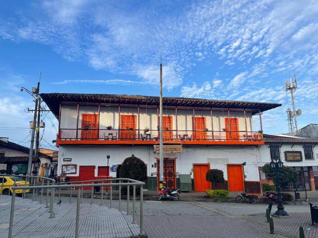 a white building with orange doors and a balcony at Hotel Colonial Abejorral in Abejorral