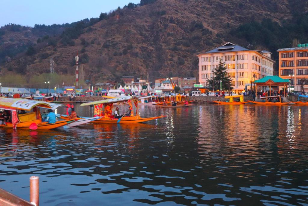 a group of boats in a body of water with buildings at House Boat New Pala Palace in Srinagar