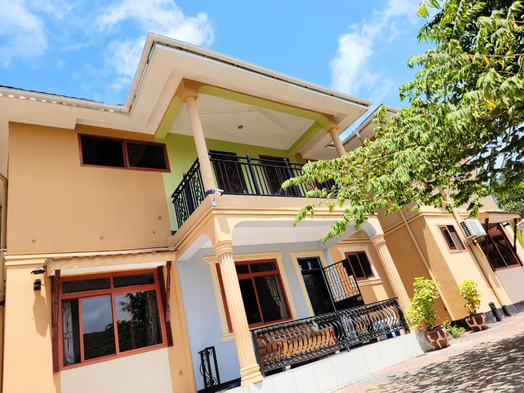 a large yellow house with a balcony at Jm Lodge - Kunduchi in Dar es Salaam