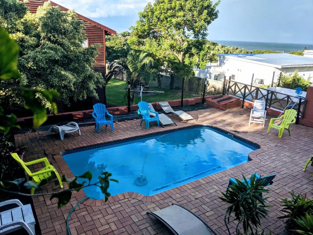 a swimming pool with chairs and a patio at Indigo Chalets in Port Edward