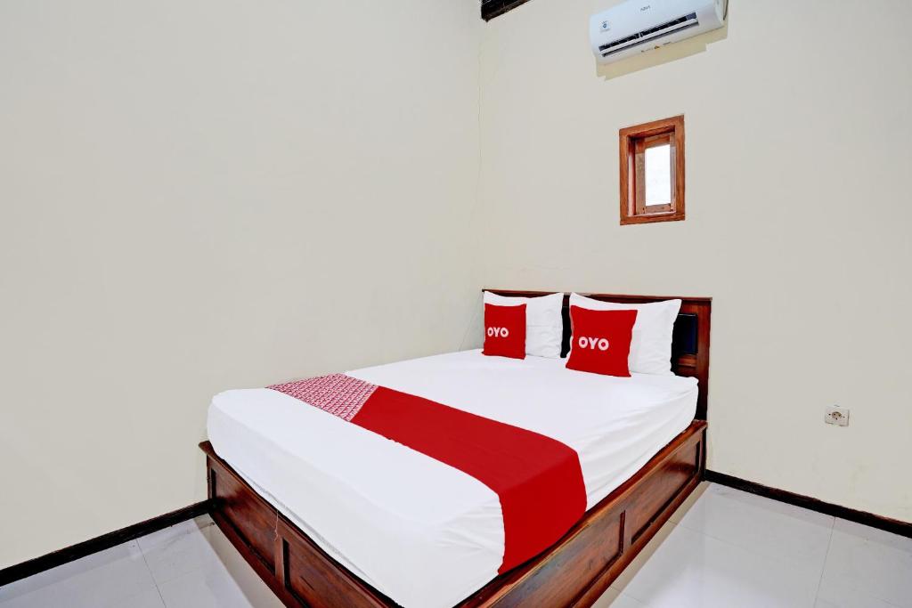 a bedroom with a bed with red pillows at OYO 92367 Garuda Homestay Syariah in Banyuwangi