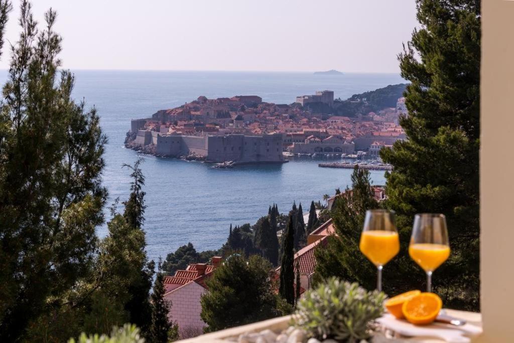 dos vasos de zumo de naranja sentados en una cornisa con vistas a una ciudad en Sea View Apartments, en Dubrovnik