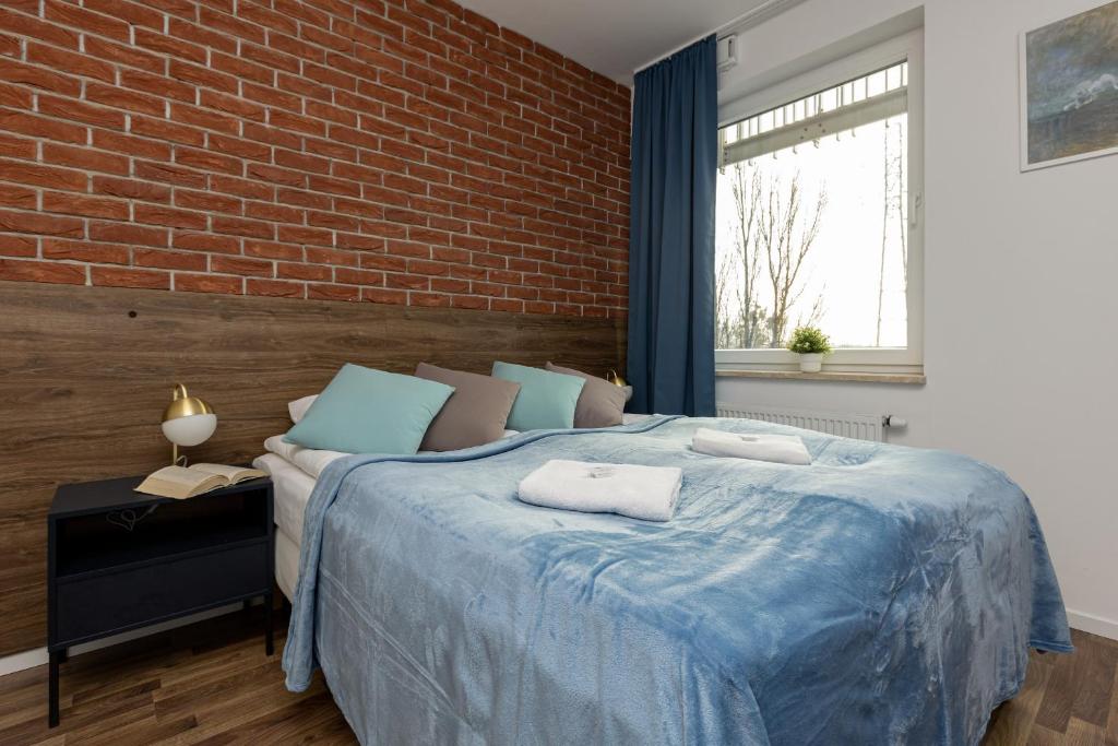a bedroom with a blue bed with a brick wall at Stacja Wola Apartments with Parking by Renters in Warsaw