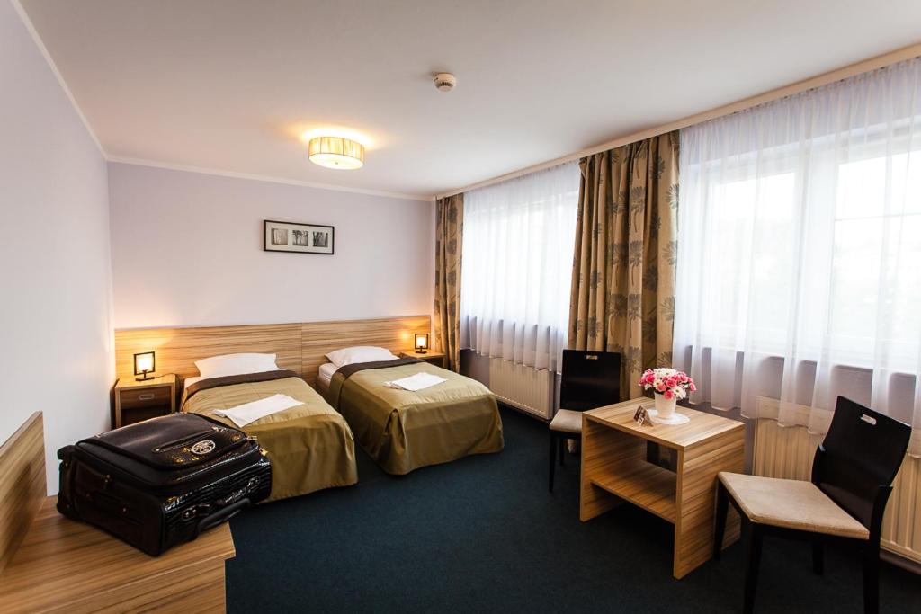 Cette chambre comprend 2 lits et une table. dans l'établissement Hotel Alpex, à Zabrze
