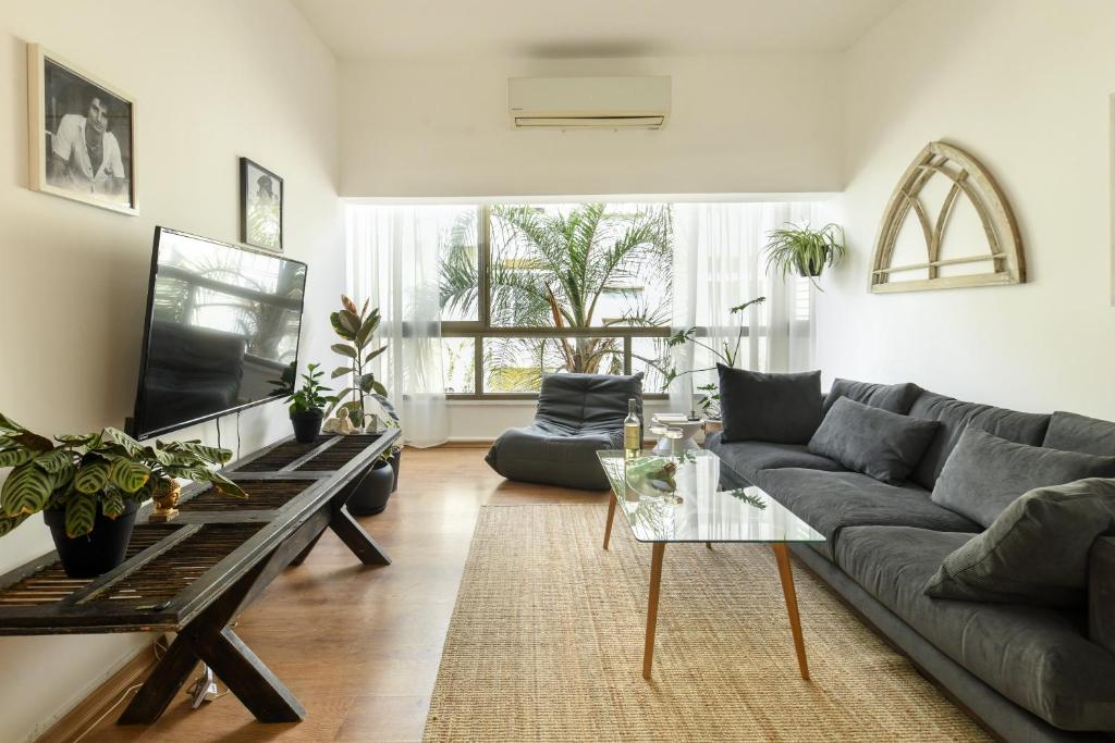 uma sala de estar com um sofá e uma mesa em Cozy 2BR Apt w Green Oasis a 3 Min Walk from Beach by Sea N' Rent em Tel Aviv