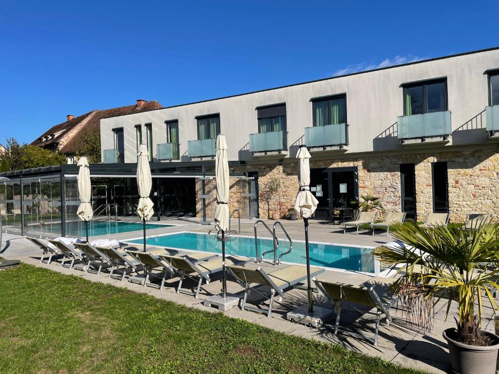 a hotel with a swimming pool with chairs and umbrellas at Kaiser von Österreich, Historik- und Thermalhotel in Bad Radkersburg