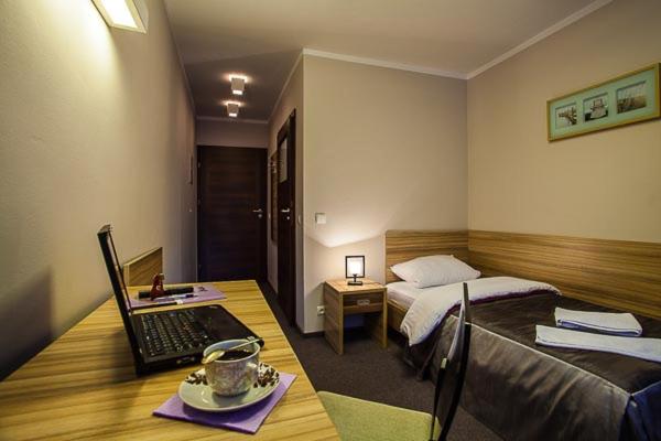 Schlafzimmer mit einem Bett und einem Schreibtisch mit einem Laptop in der Unterkunft Hotel Alpex View in Zabrze