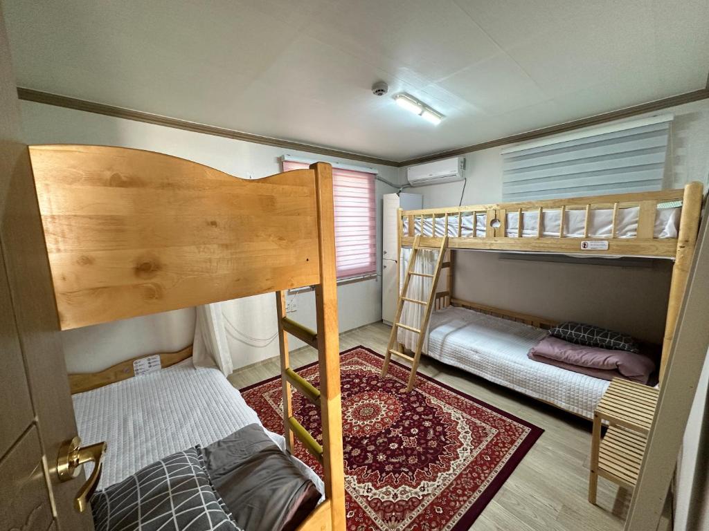 een slaapkamer met 2 stapelbedden en een tapijt bij SOYA`S HOUSE in Busan