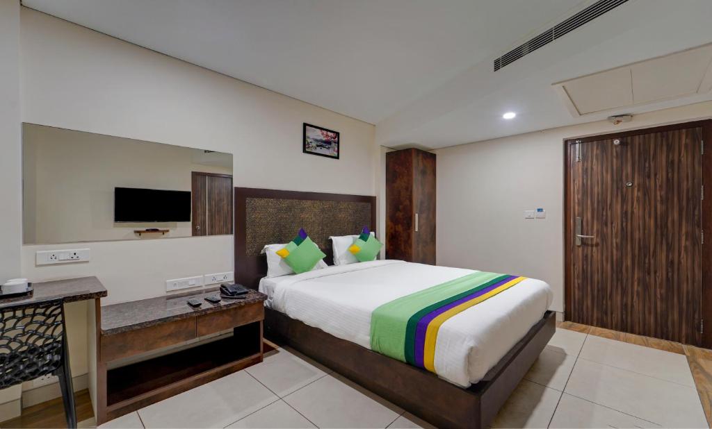 a bedroom with a bed and a desk and a television at Treebo Vetri Supreme Residency in Chennai
