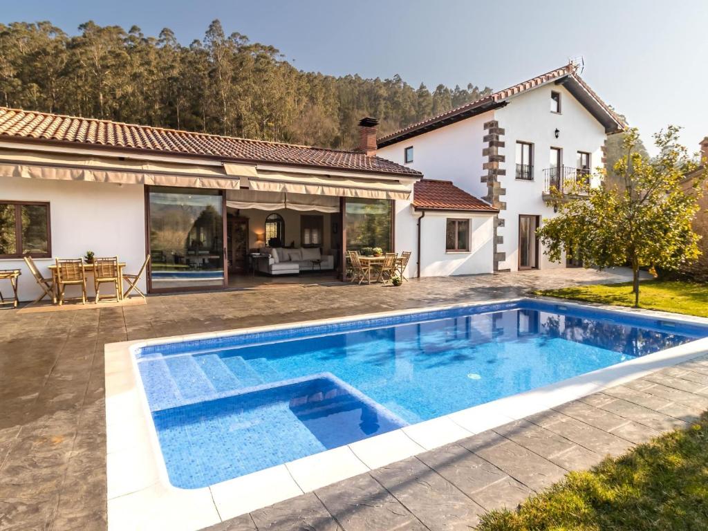 une villa avec une piscine en face d'une maison dans l'établissement Impresionante villa entre mar y montaña, à La Cavada