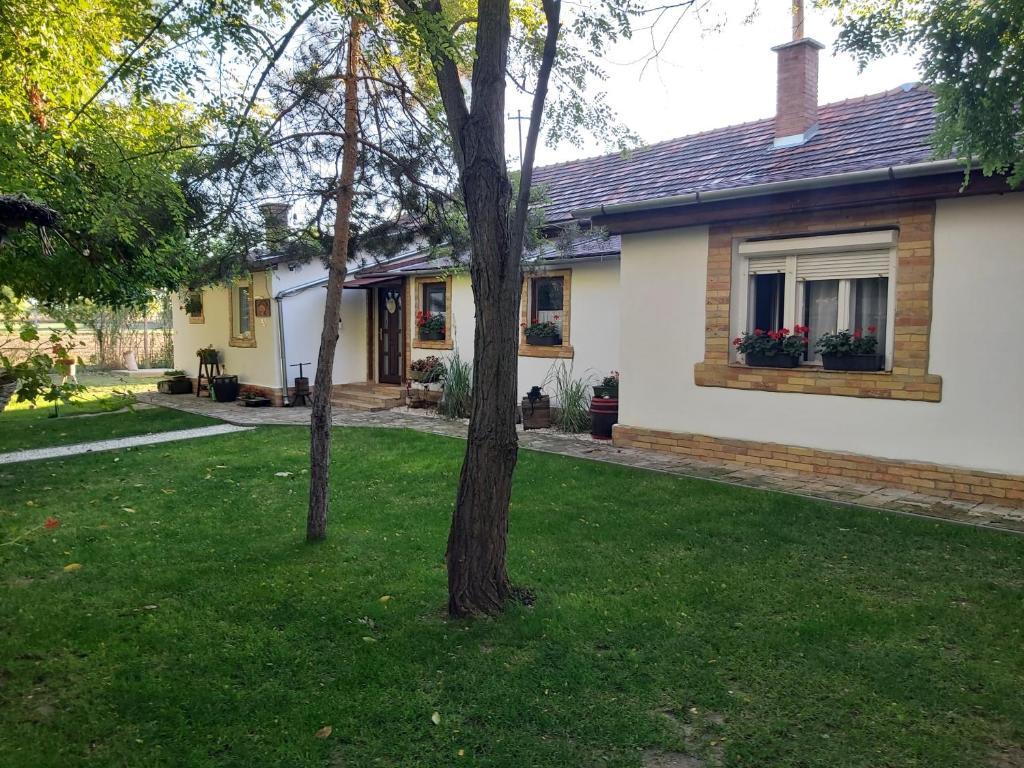 una casa con dos árboles en el patio en Józsa Tanya, en Cegléd