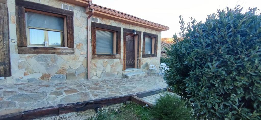 Casa de piedra con ventana y pasarela de piedra en Casas Navarredonda, en Navarredonda