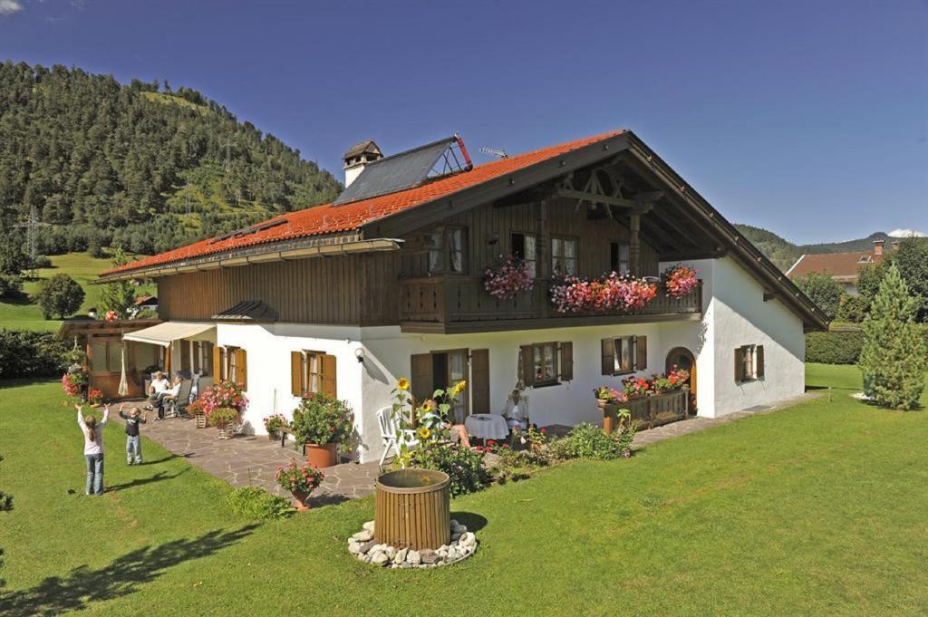 een groot huis met mensen die ervoor staan bij Ferienwohnung Alpenwelt in Wallgau