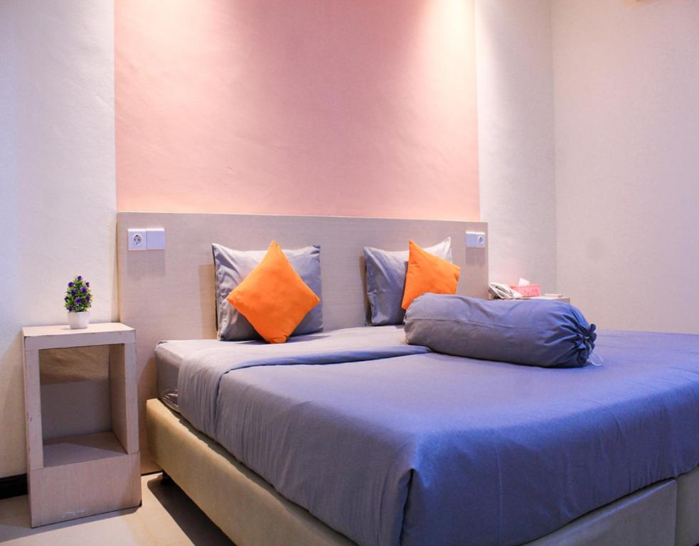 a bedroom with a bed with blue sheets and orange pillows at Suzuya Hotel Bagan Batu in Bagansinembah