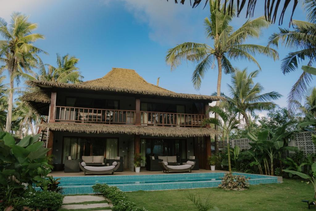 a villa with a swimming pool and palm trees at Domu Mia Villa Siargao in General Luna