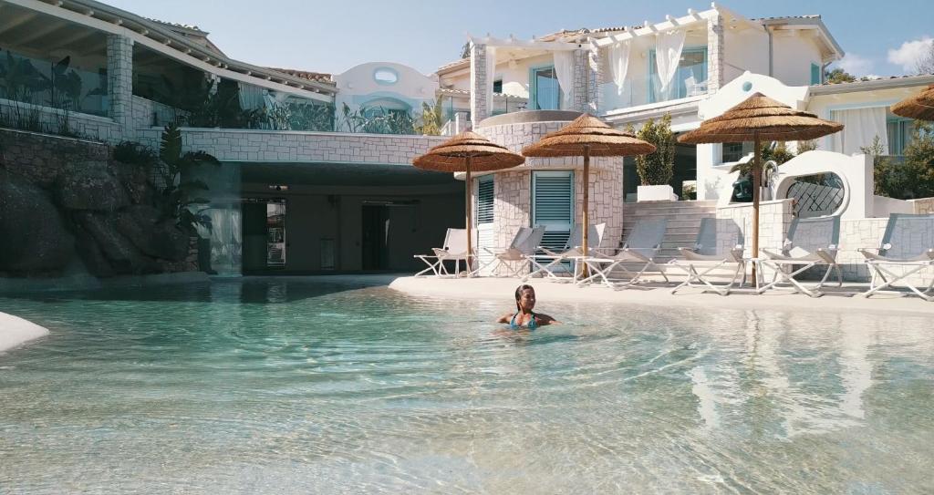Una donna è in acqua in una piscina di Oasi Blu Sardinia a Santa Margherita di Pula