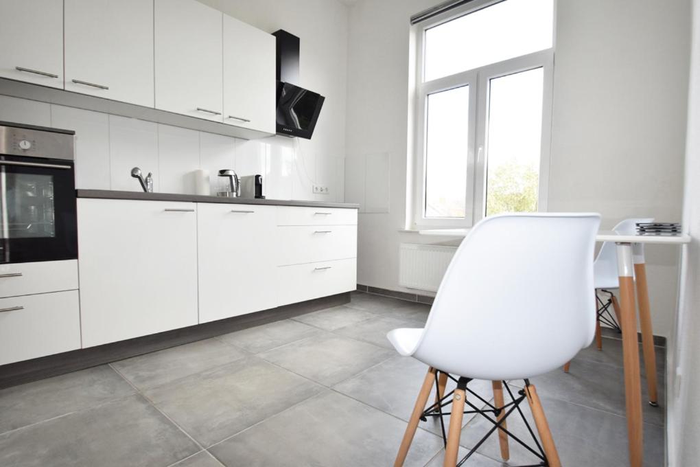a white kitchen with a white chair and a table at Air Apartments 3 in Bremen