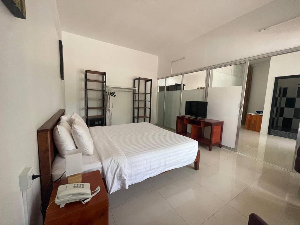 a bedroom with a white bed and a television at La Rivière d' Angkor Resort in Siem Reap
