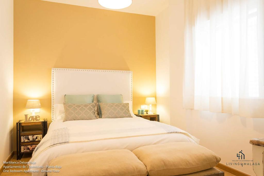 Living4Malaga Boutique Apartments في مالقة: غرفة نوم مع سرير أبيض كبير مع نافذة