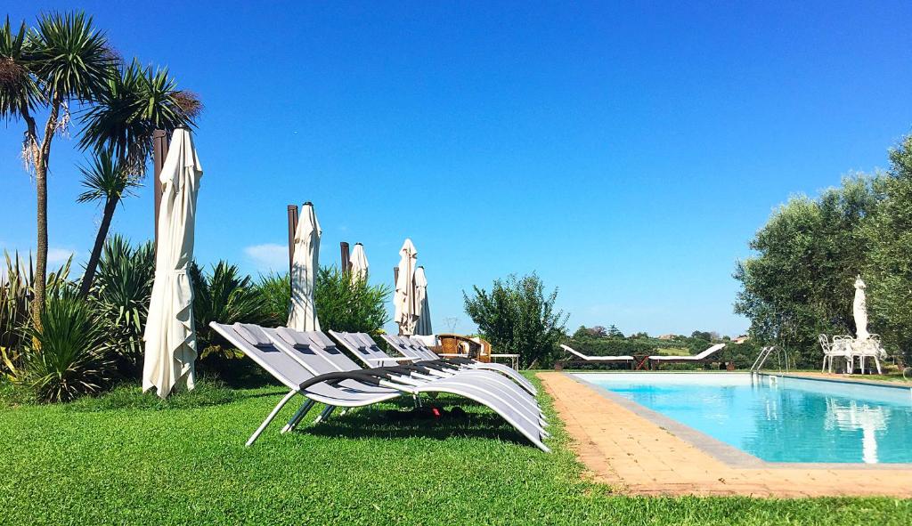 een witte loungestoel naast een zwembad bij Villa con pascina panoramica in Bracciano