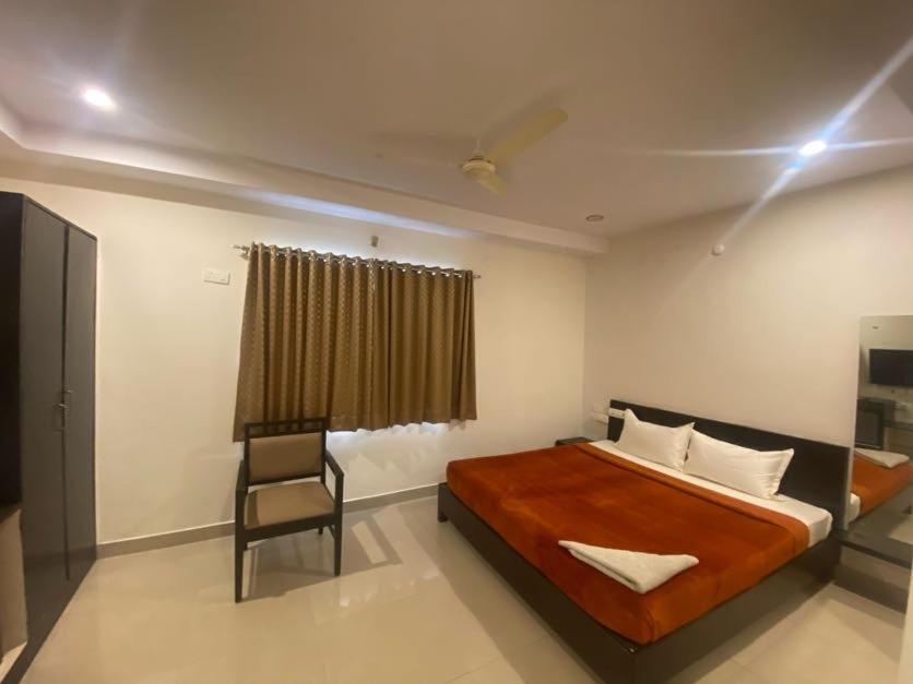 a bedroom with a large bed and a chair at SHLOKA RESIDENCY in Shamshabad