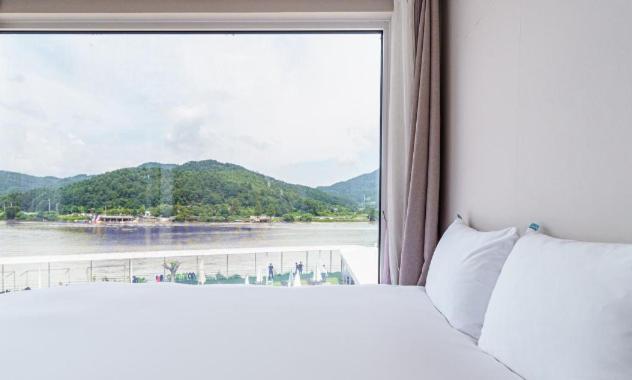 a bedroom with a window with a view of a river at Gapyeong Parotia Waterhouse in Gapyeong