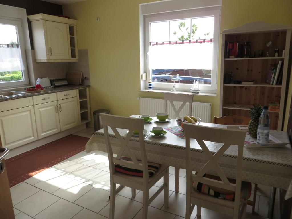 a kitchen with a table and chairs and two windows at NEU Nordseeferienhaus An der Mühle in Westerholt