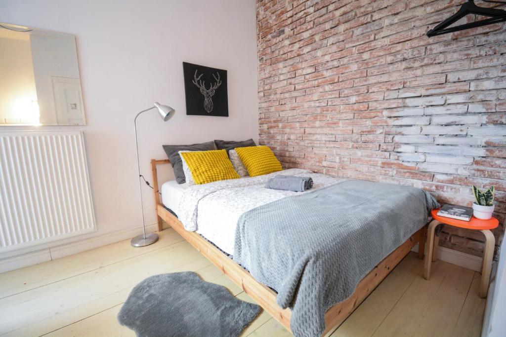 a bed in a room with a brick wall at LION apartments - Gold in Krakow