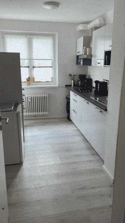 cocina con armarios blancos y suelo de madera en Ferienwohnung Frieda, en Delmenhorst