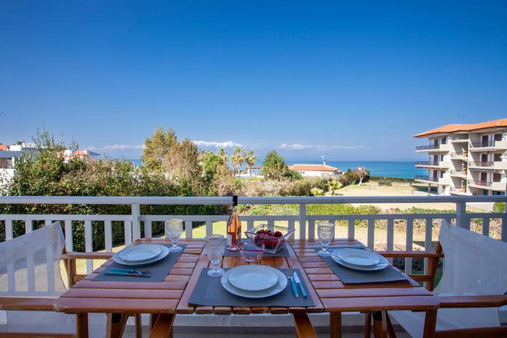 een houten tafel op een balkon met uitzicht op de oceaan bij Calypso beach front apartment in Hanioti