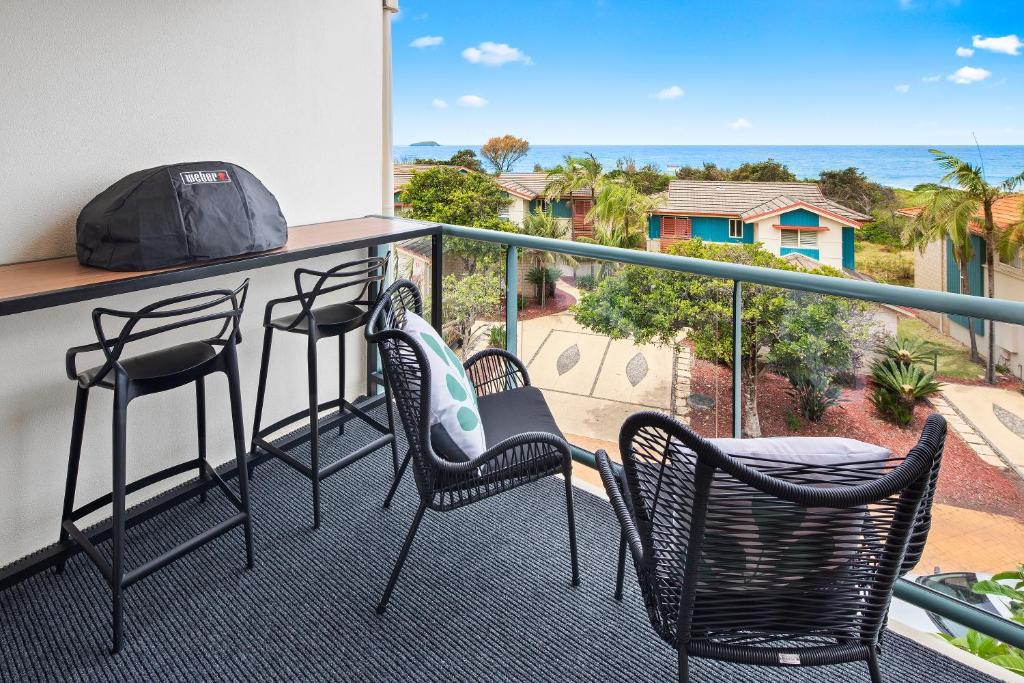 a balcony with chairs and a bar with a view of the ocean at Ocean View Apartment - Aqualuna Coffs Harbour in Sapphire Beach