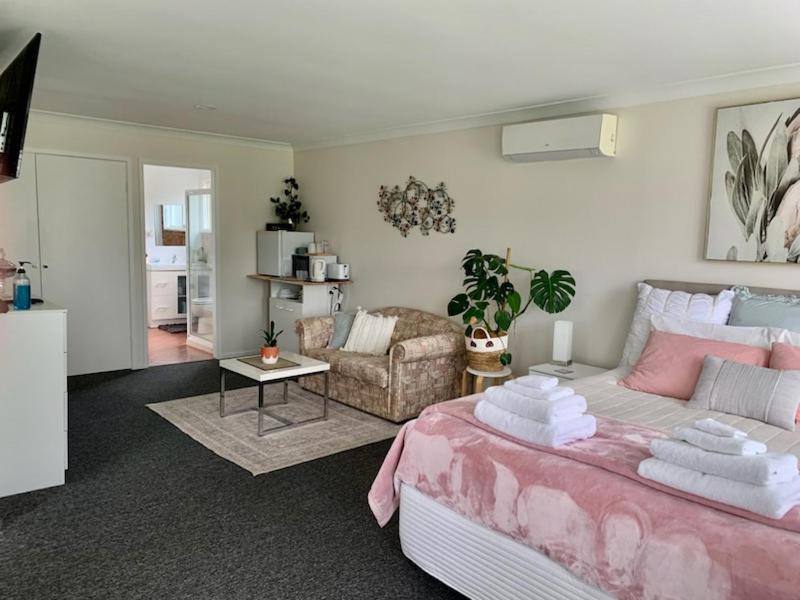 um quarto com uma cama rosa e uma sala de estar em Tynedale Cottage Bowral em Bowral