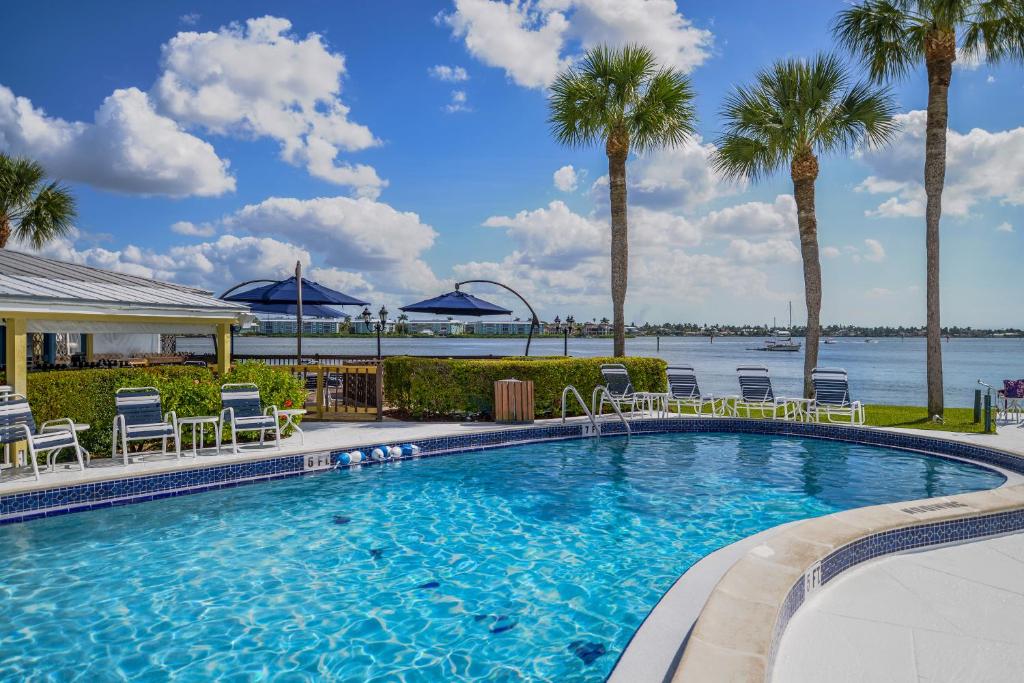 a swimming pool with chairs and palm trees at Charter Club Resort Of Naples Bay in Naples