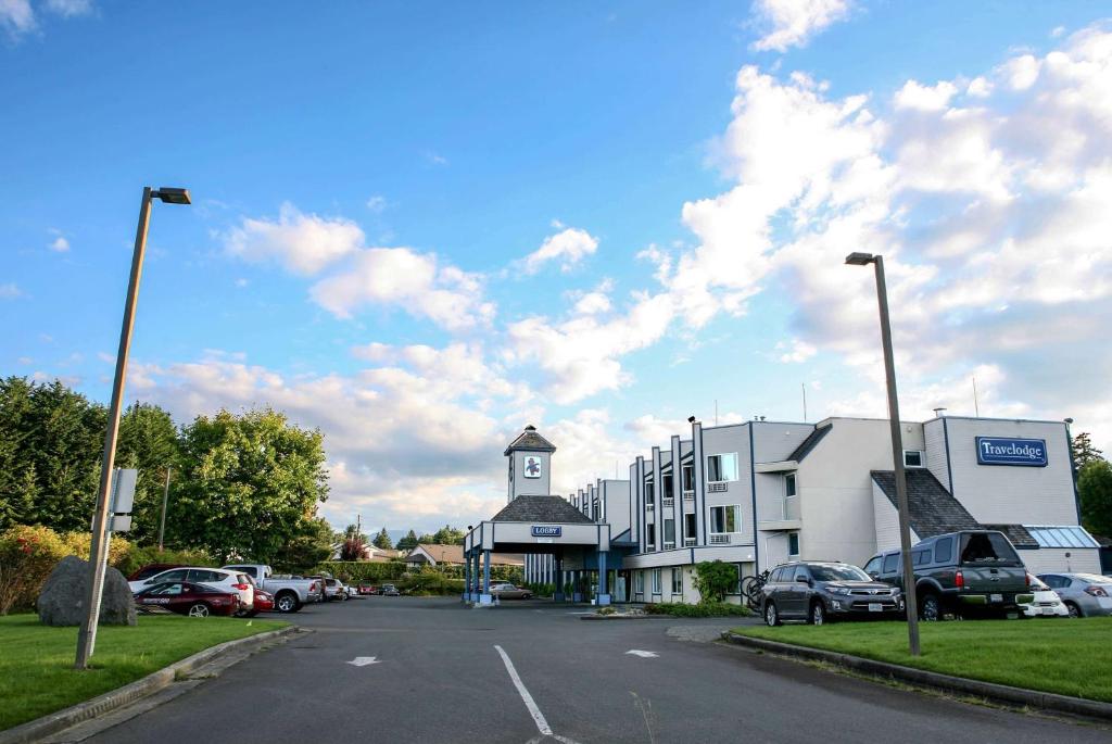 um edifício com uma torre de relógio ao lado de um parque de estacionamento em Travelodge by Wyndham Parksville em Parksville