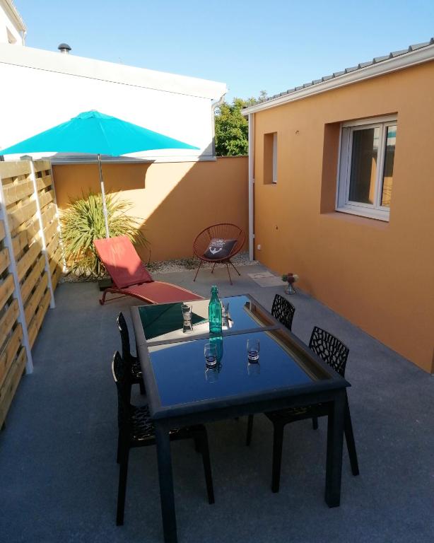un patio avec une table, des chaises et un parasol dans l'établissement Maison de vacances entre plage et port, à La Chaume