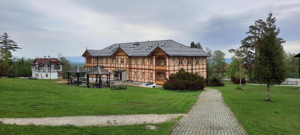 una gran casa de madera con un parque infantil delante de ella en Vila Kollár Apartmán 2, en Vysoké Tatry