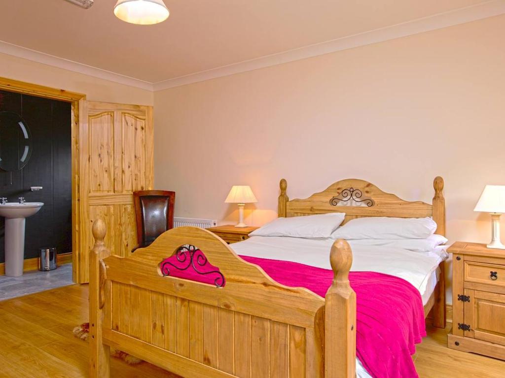 a bedroom with a large wooden bed and a sink at Fern Wood Estate in Glengarriff