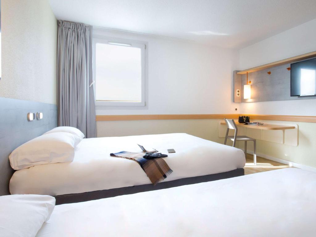フレジュスにあるIbis Budget Fréjus St Raphaël plagesのベッド2台とデスクが備わるホテルルームです。