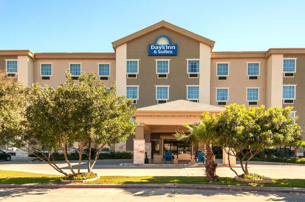 una vista frontal de un hotel con árboles en la parte delantera en Days Inn & Suites by Wyndham San Antonio near Frost Bank Center en San Antonio