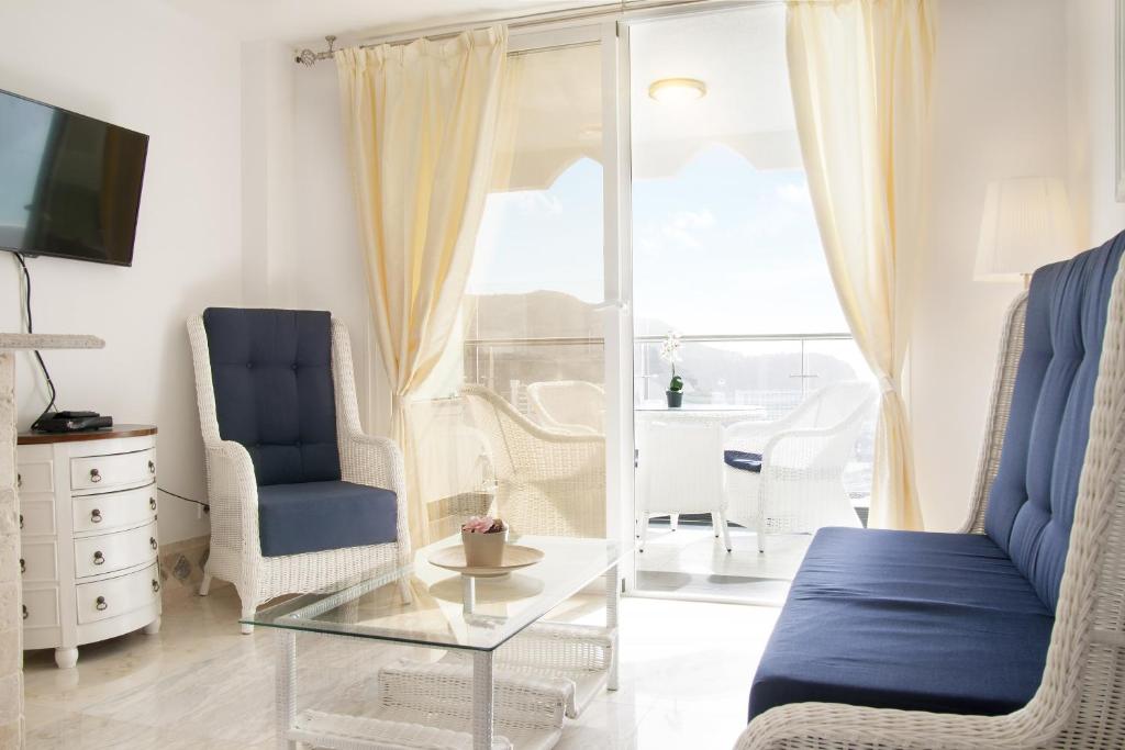 a living room with a glass coffee table and blue chairs at Villa Magna in Puerto Rico de Gran Canaria