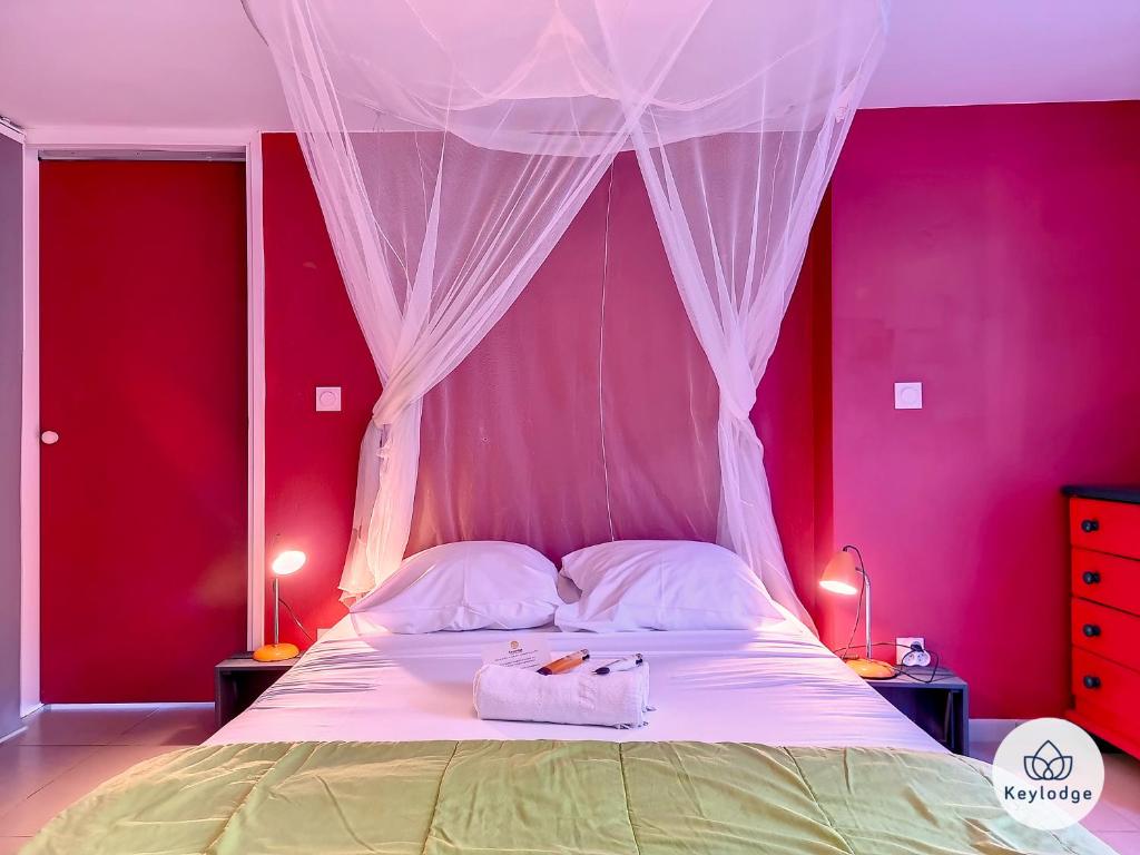 - une chambre avec des murs roses et un lit à baldaquin dans l'établissement Ti Caz Serré - T2 de 40 m2 à l'Entre-Deux, à Entre-Deux