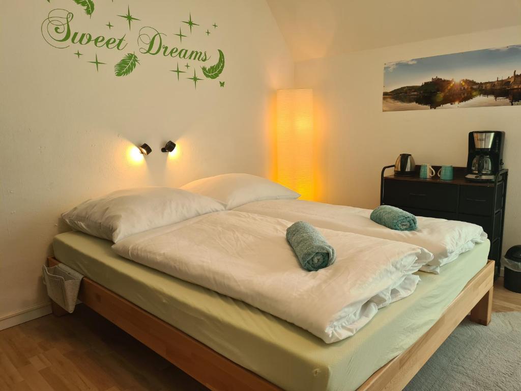 - un lit avec des draps et des oreillers blancs dans une chambre dans l'établissement Lichtdurchflutetes Zimmer - Käppele, à Waldbüttelbrunn