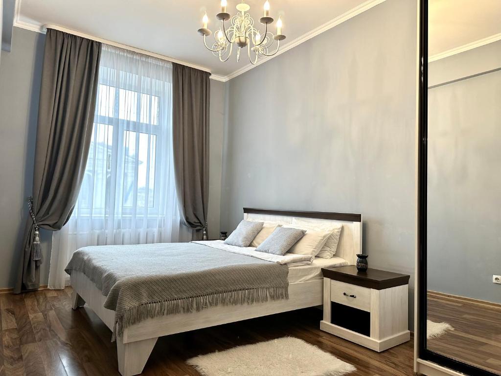 a bedroom with a bed and a chandelier at Lux apartments in the city center, with a view of the theater, near Zlata Plaza in Rivne