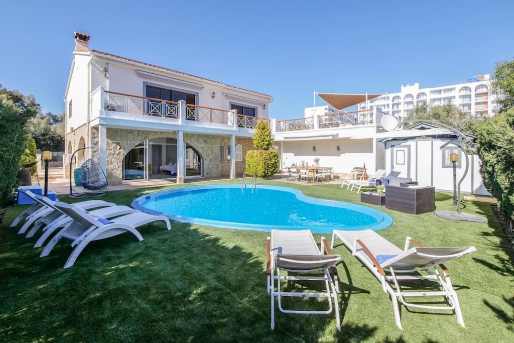 una villa con piscina e sedie in un cortile di Moderne Villa, Pool+Meerblick,schnelles Wifi,Klima a Calas de Mallorca