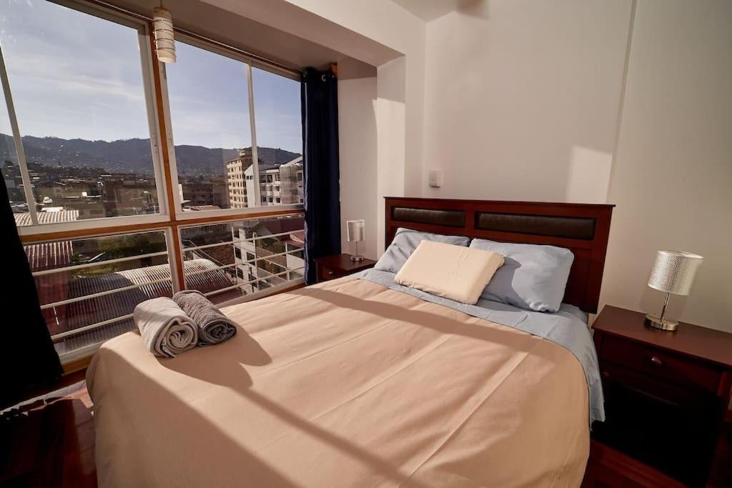 um quarto com uma cama e uma grande janela em Amarus Apartment em Cusco