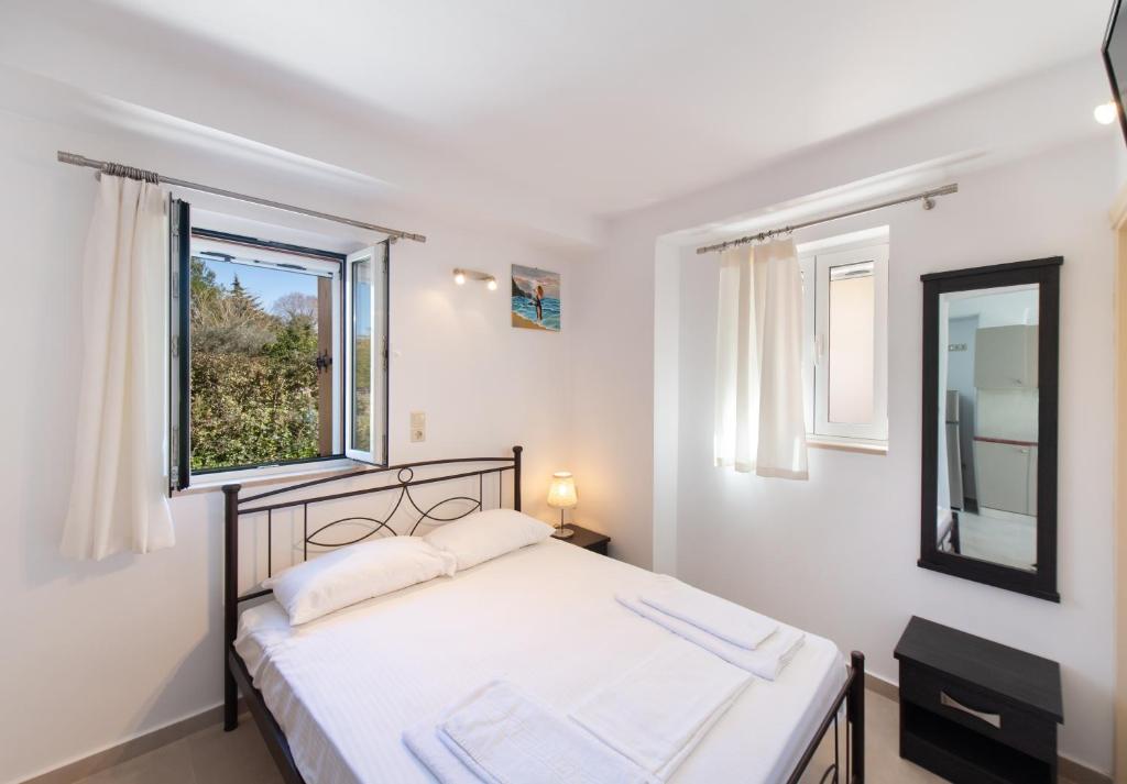 a bedroom with a bed and a window at Boursinos cozy apartments by Imagine Lefkada in Lefkada Town