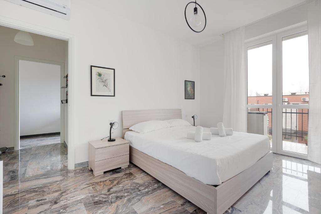 a white bedroom with a large bed and large windows at Dergano Comfy Apartment - 250 m far from M3 in Milan